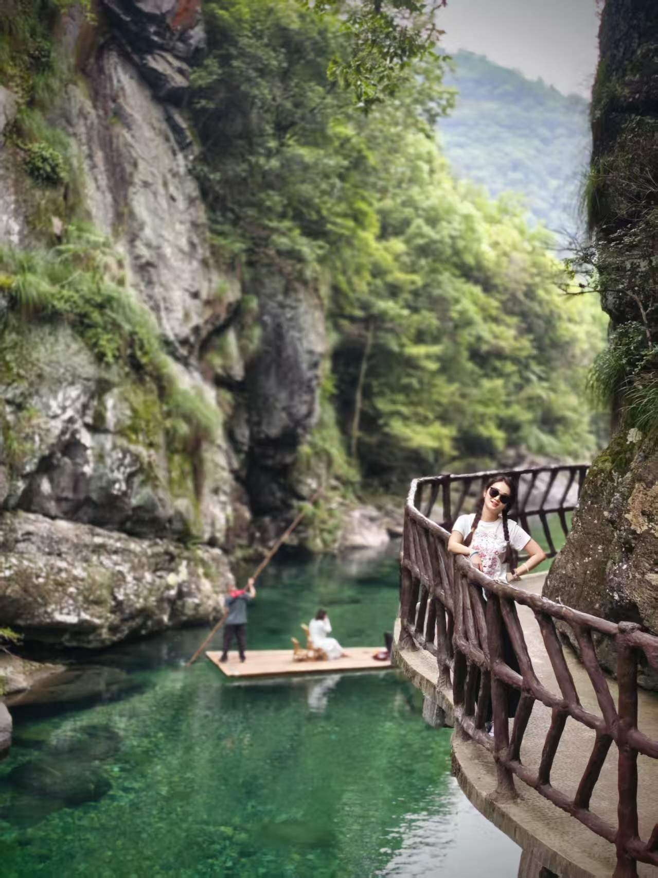 Canyon path above emerald water with a small raft below
