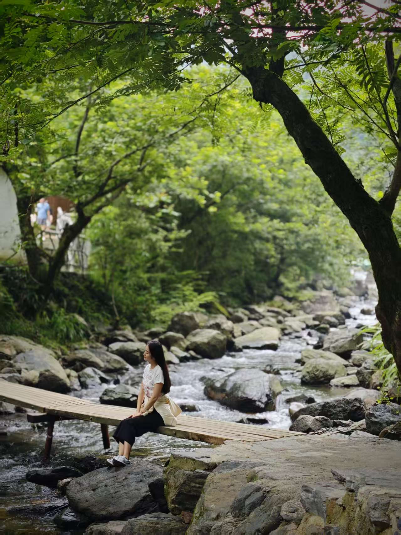 Traveler sitting quietly on a wooden bridge over a stream