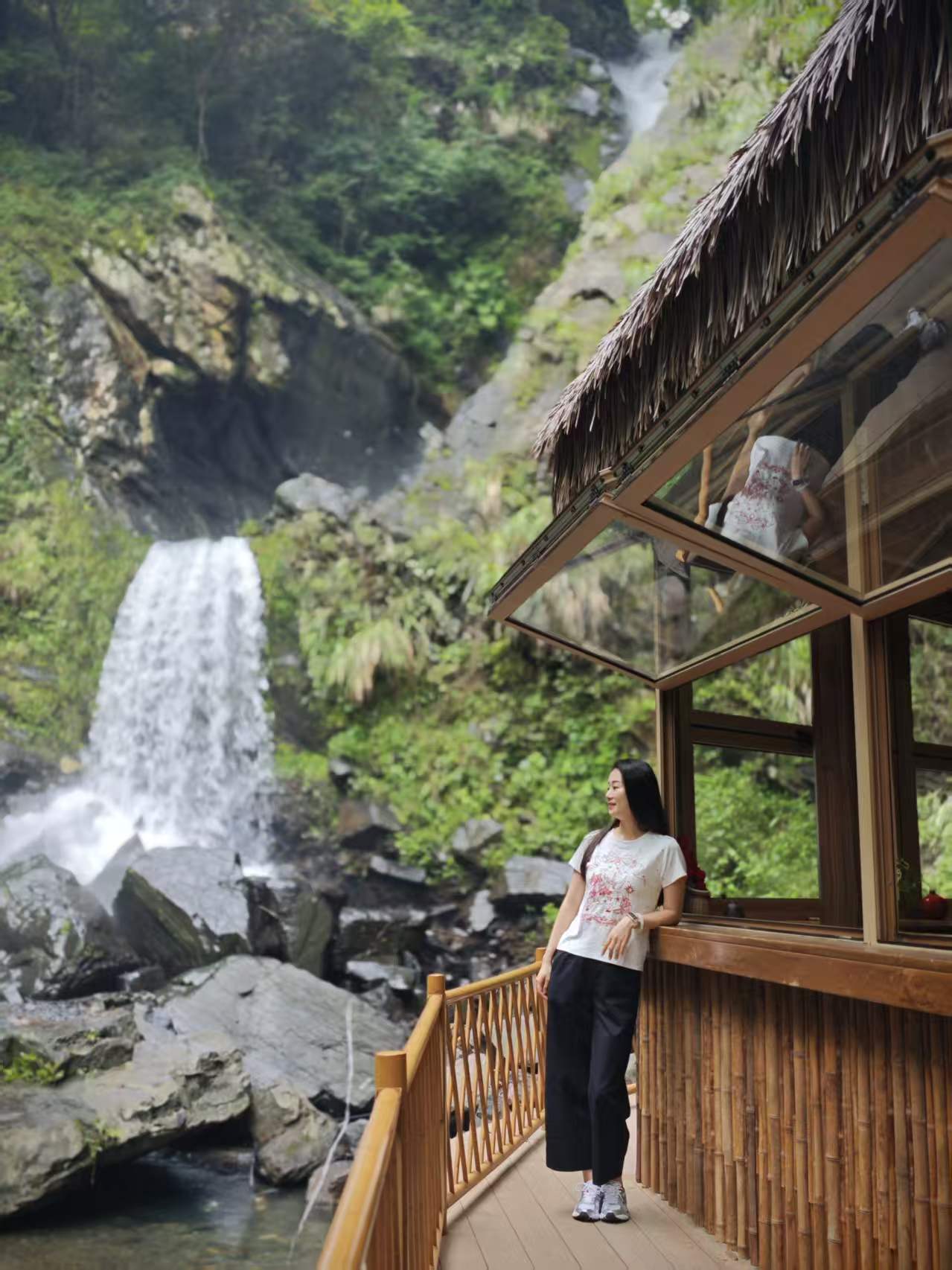Waterfall and wooden pavilion in a lush canyon